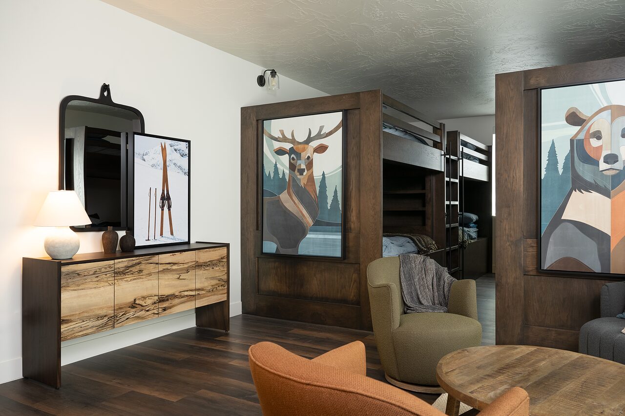 Bunk room with dark wood built-in beds, a leather chair, a round wood table, and playful animal portraits on the walls