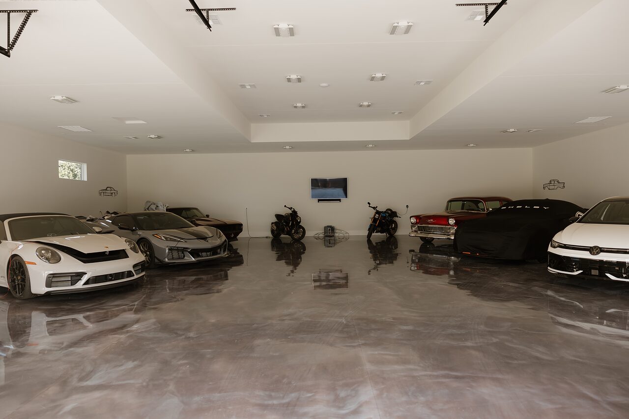 Garage interior with a polished, reflective poured floor, white walls, a recessed ceiling tray, and evenly spaced recessed lights